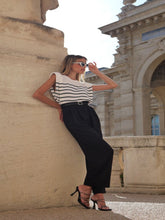 A woman wears striped tank top and high-waisted pants